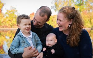 A joyful family shares a tender moment together outdoors against a backdrop of autumn foliage.