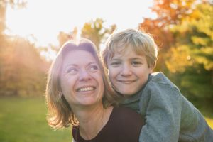 A warm embrace captured during golden hour with autumn trees in the background.