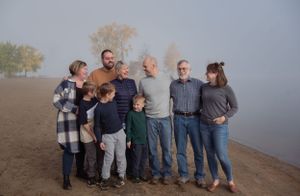 Family members gathered together for a portrait on a foggy beach.