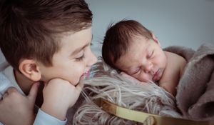 Two children share a quiet moment while resting on soft bedding.