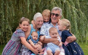 A multi-generational gathering under a weeping willow tree on a sunny day.