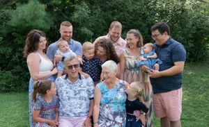 A large extended family poses together for a casual outdoor summer portrait.