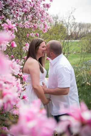A romantic moment captured beneath blooming pink magnolia trees in a spring garden setting.