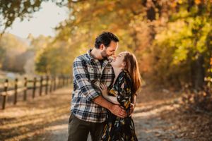husband and wife laugh at each other while hugging on path through fall trees in Chattanooga