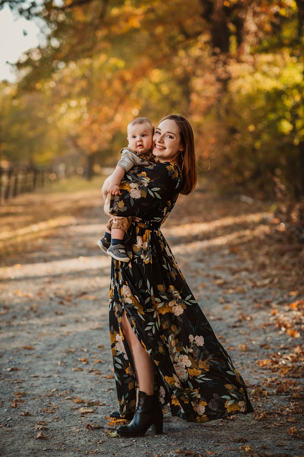 mother in long black dress holds baby boy on tree lined path in Fall for Chattanooga mini sessions
