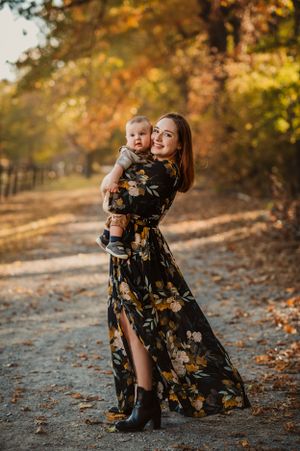 mother in long black dress holds baby boy on tree lined path in Fall for Chattanooga mini sessions