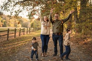 A joyful group celebrates with raised arms while walking along a tree-lined path in autumn.