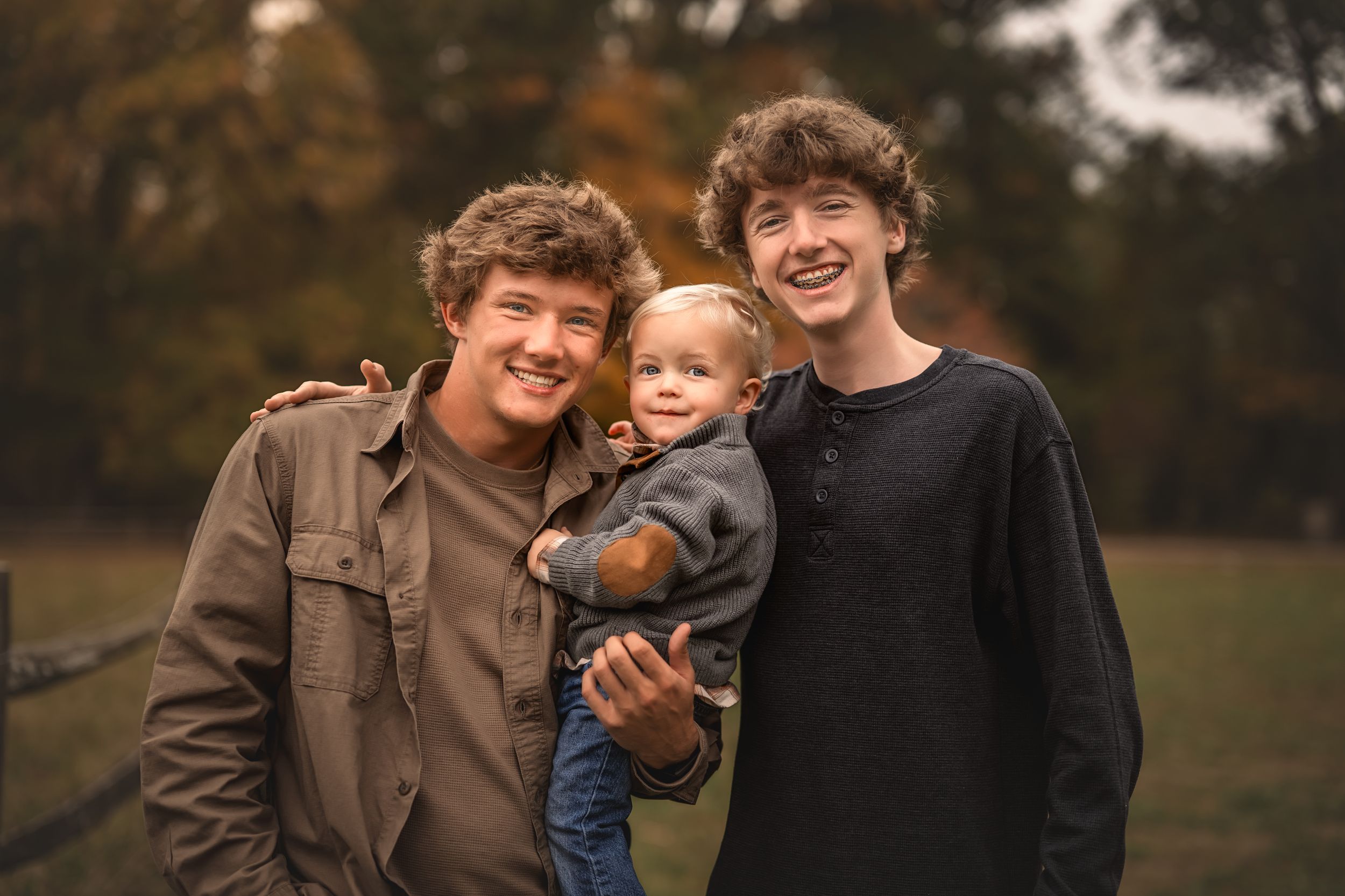 Friends laughing together outdoors during golden hour autumn photoshoot in casual attire.