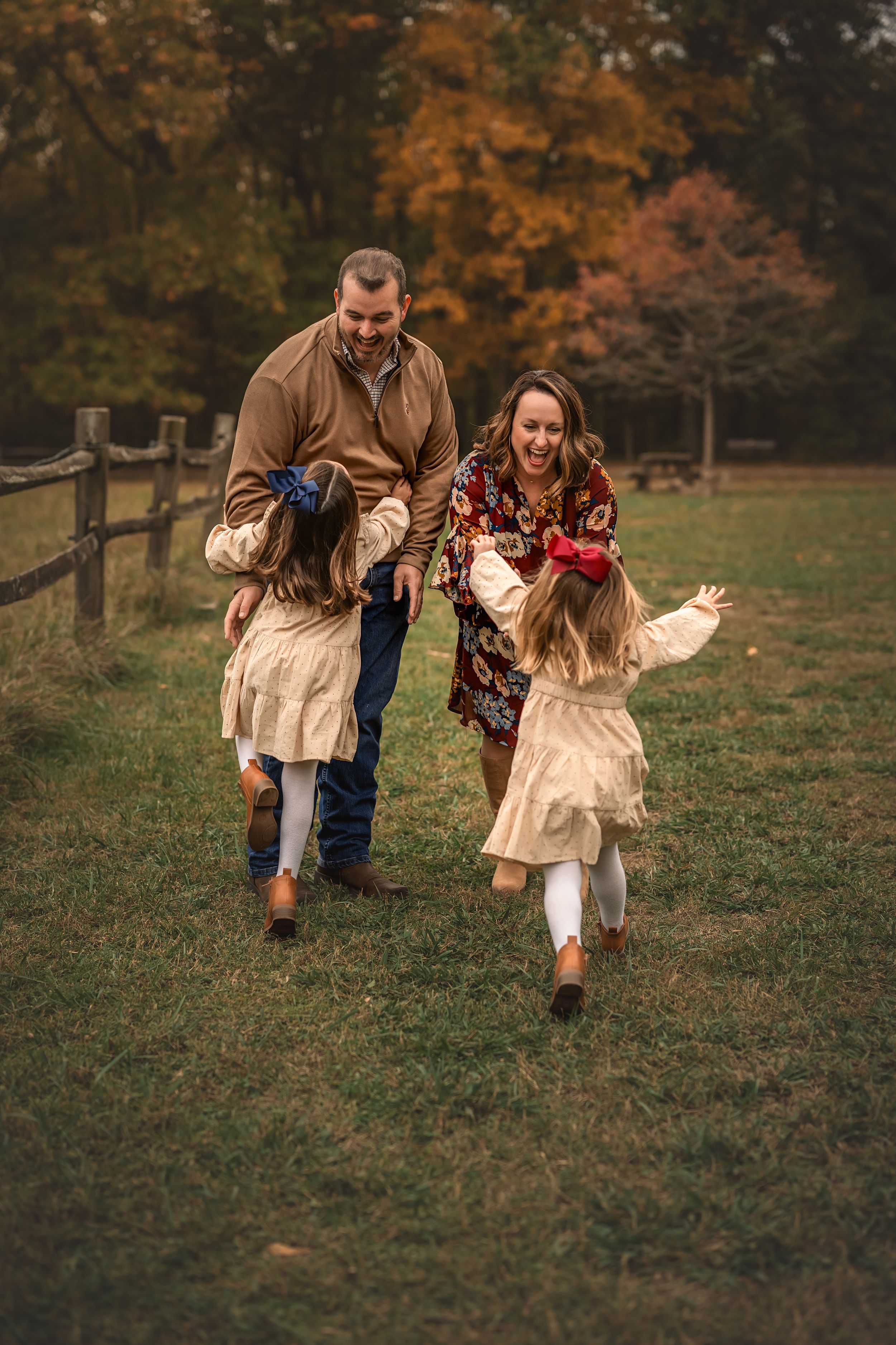 Playful game of tag being played in a grassy autumn field with trees in the background.