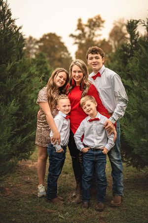 Festive family photo session among evergreen trees at a Christmas tree farm.