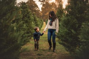 Walking hand in hand through a Christmas tree farm at sunset.