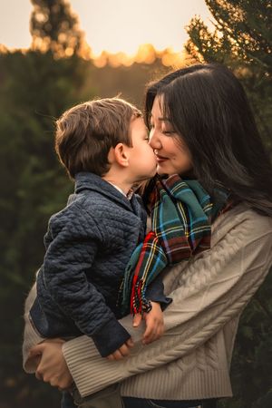A tender moment captured at sunset between parent and child among evergreen trees.
