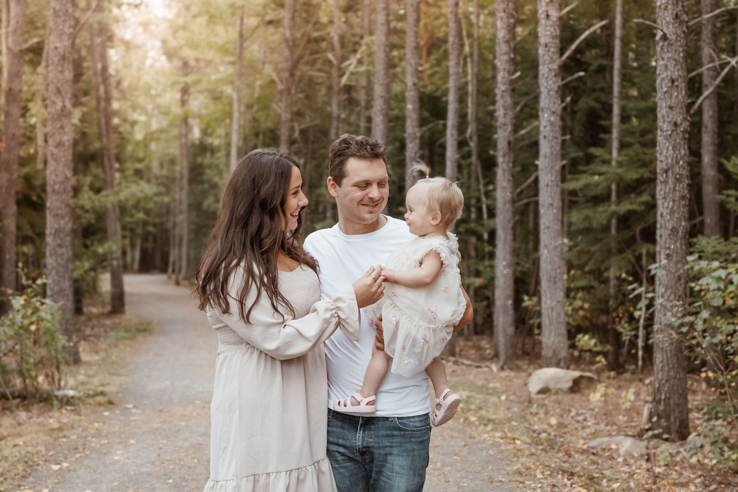 family of 3, little girl running toward mom and dad, mom and dad looking at little girl.