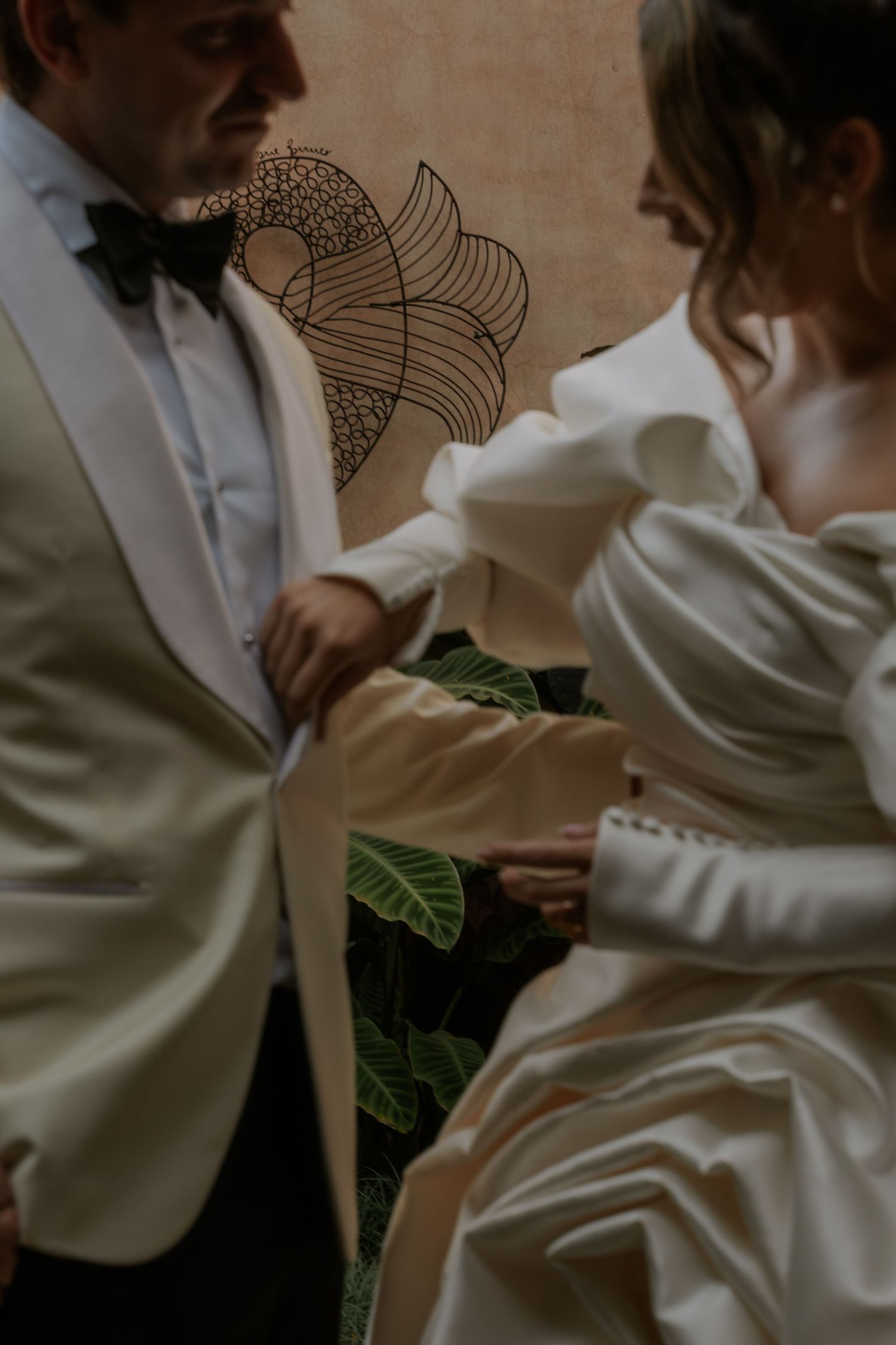 Motion-blurred artistic photo of two outstretched arms reaching towards each other in front of stone archways.
