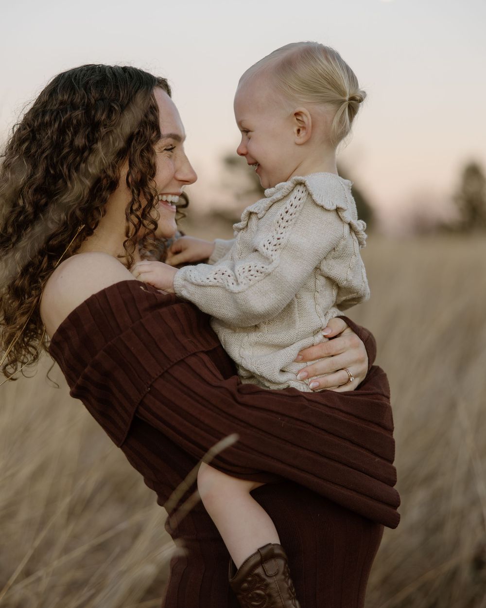 A parent and baby share intimate moments of connection in a rustic outdoor setting.