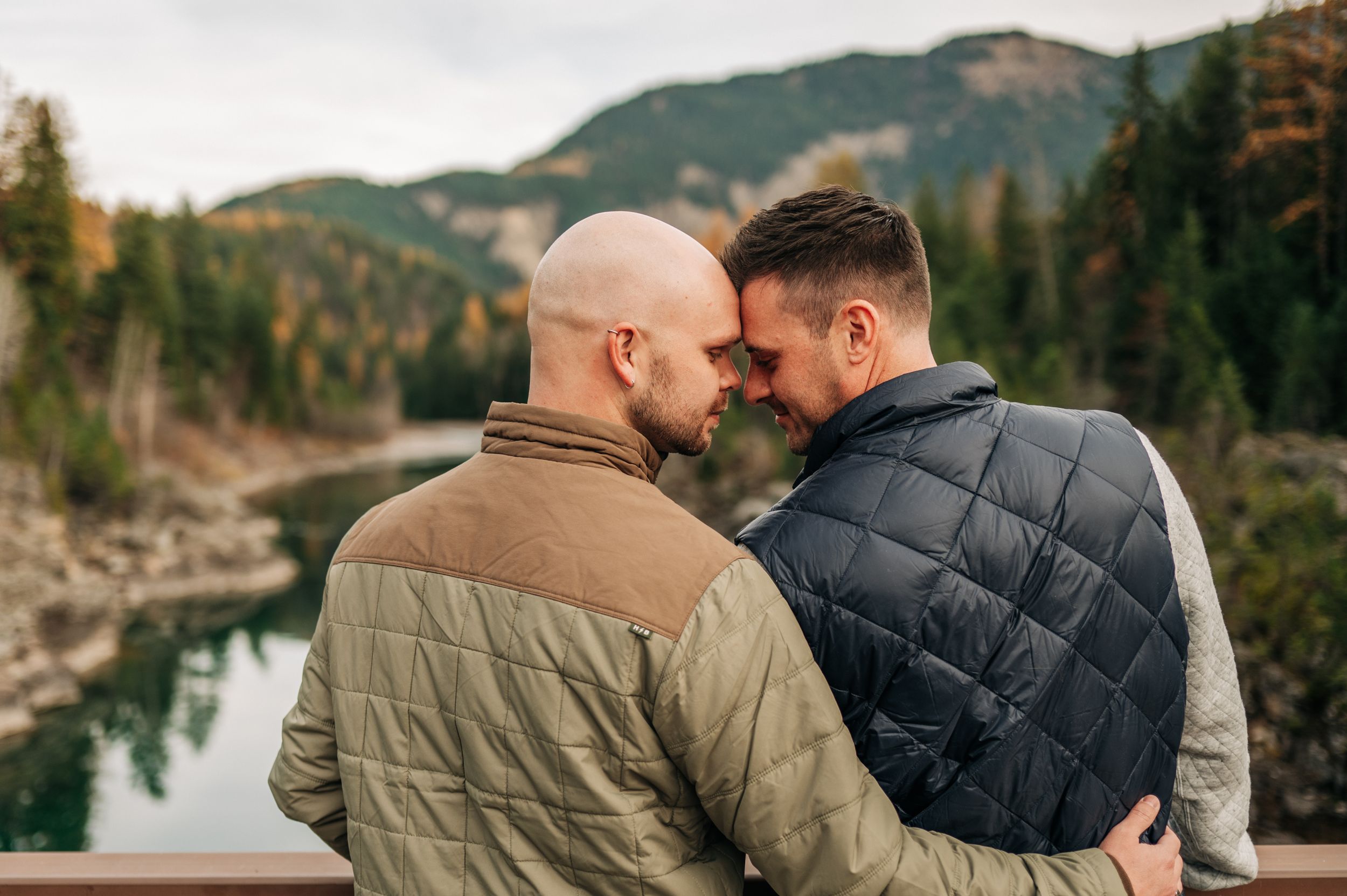 An intimate moment shared between two people on a bridge with mountain scenery.