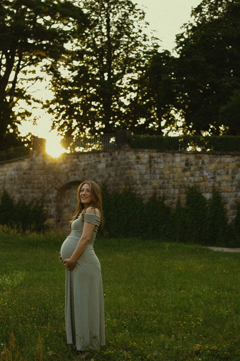Frau hält sich schwangeren Bauch im Park des Japanischen Palais - Sonnenuntergang Babybauchfotoshooting in Dresden