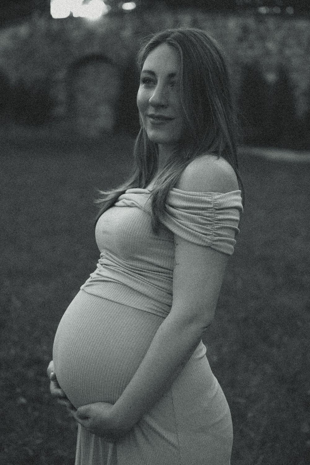 Schwangeren Portrait Fotografie Dresden - Frau steht im Kleid im Palaisgarten und hält sich mit Händen am unteren Bauch fest