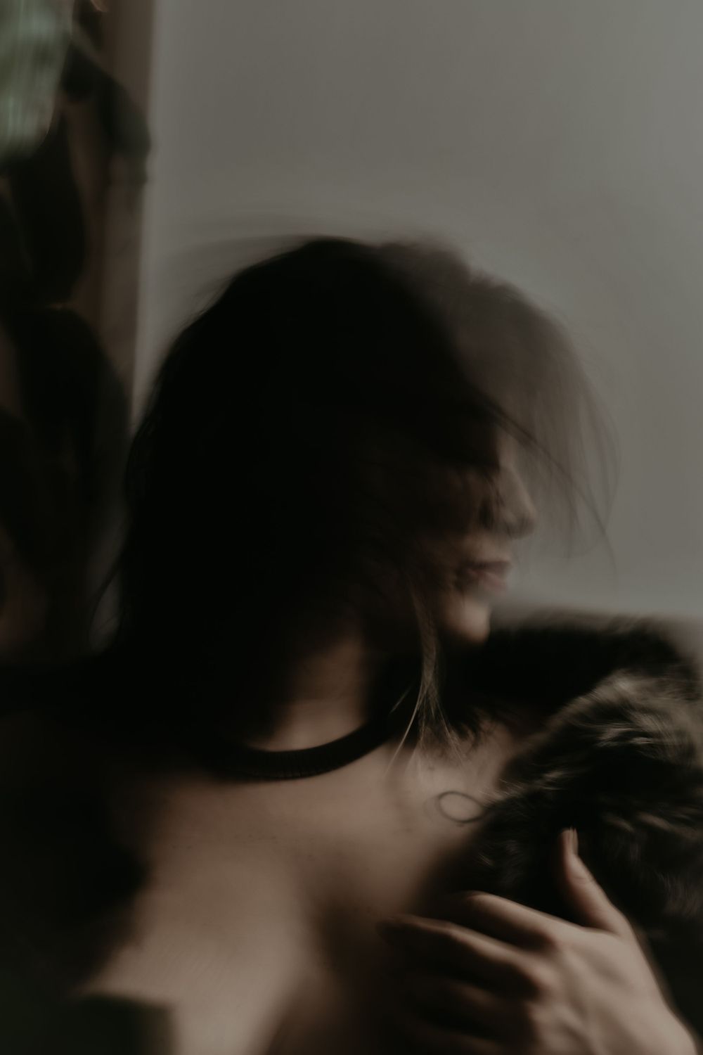 Moody atmospheric portrait photograph captured in dim lighting with blurred motion and shadows.