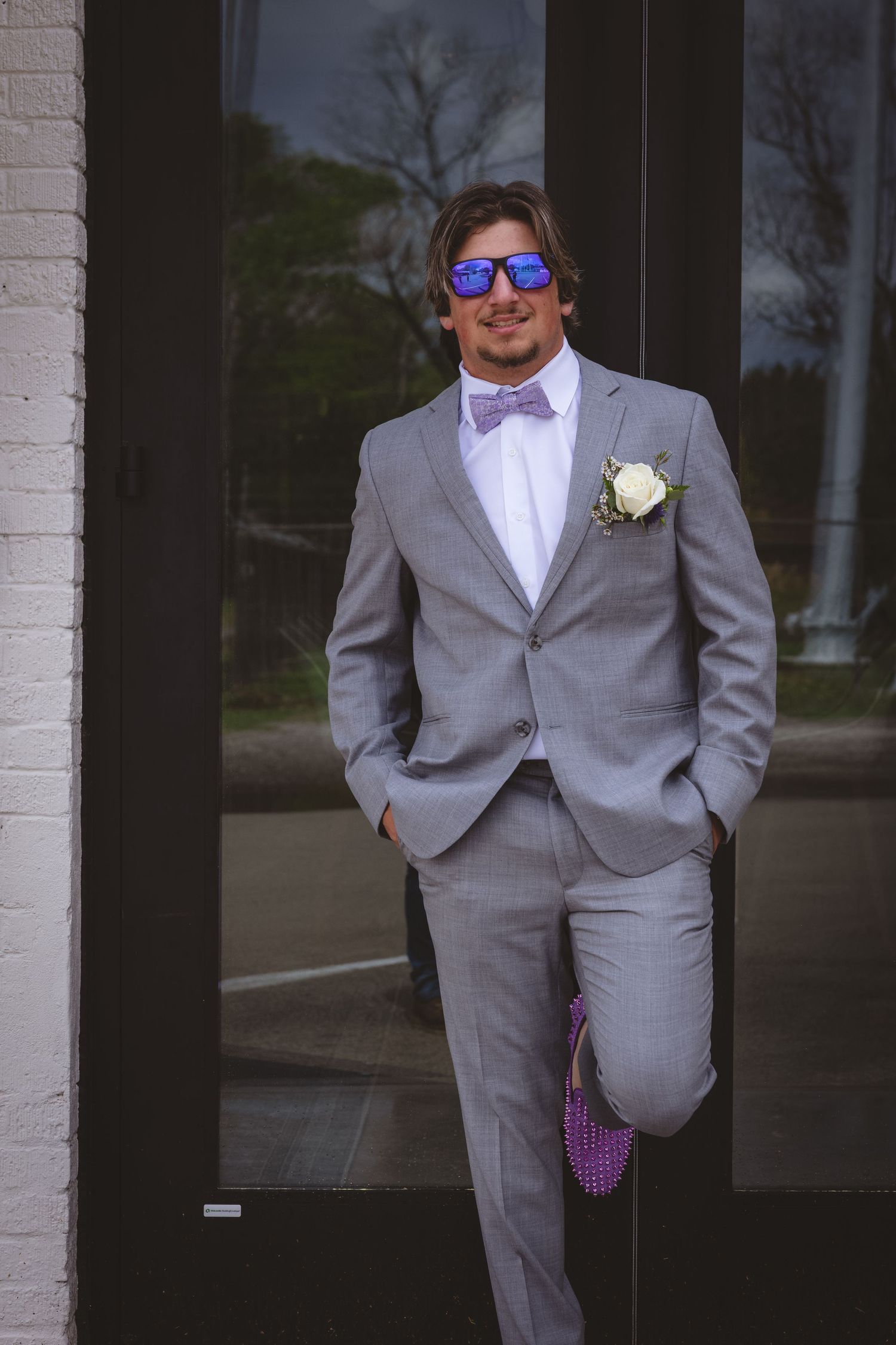 Wedding party members in light grey suits standing in a relaxed pose.