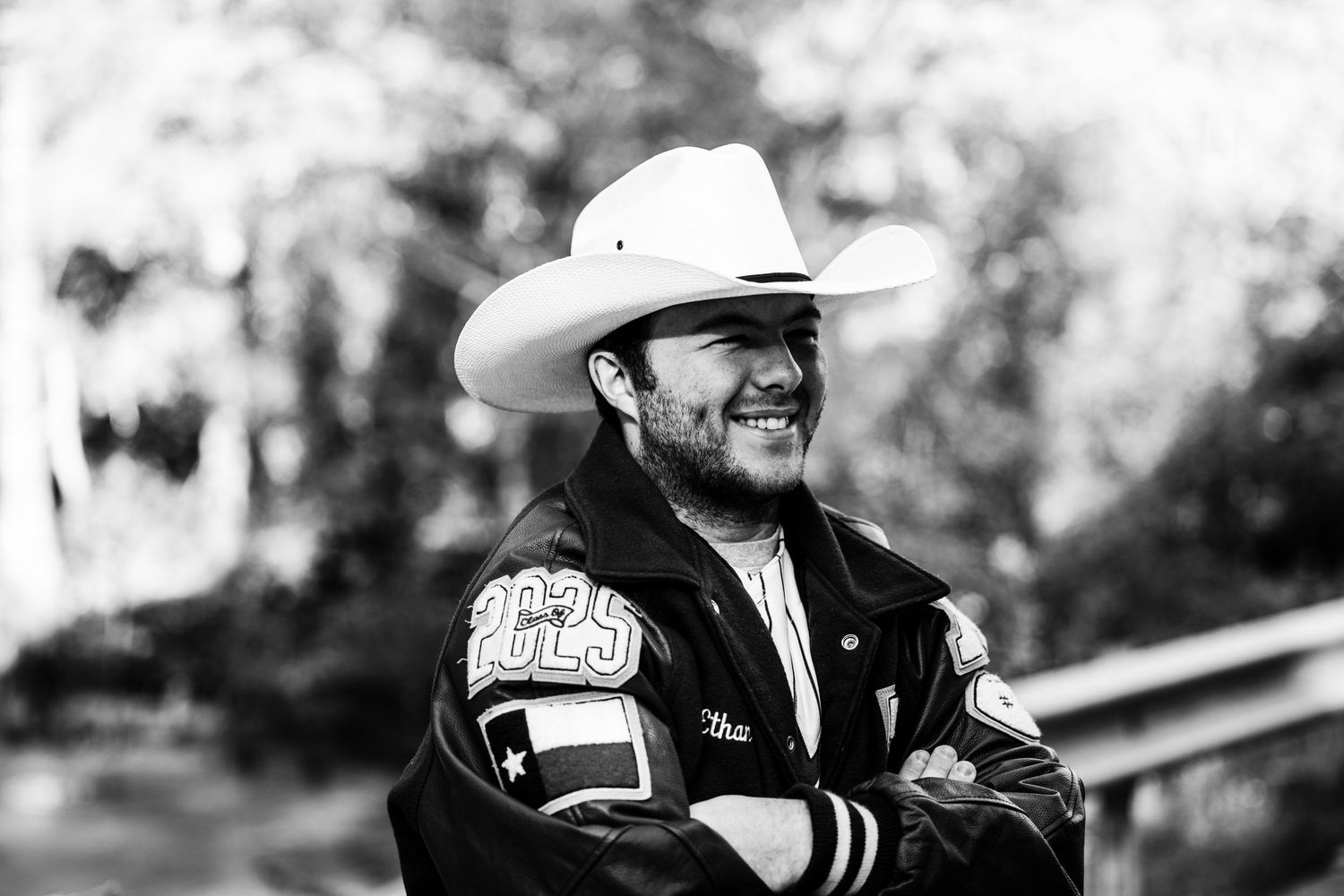 Person in western attire with cowboy hat smiling in black and white portrait.