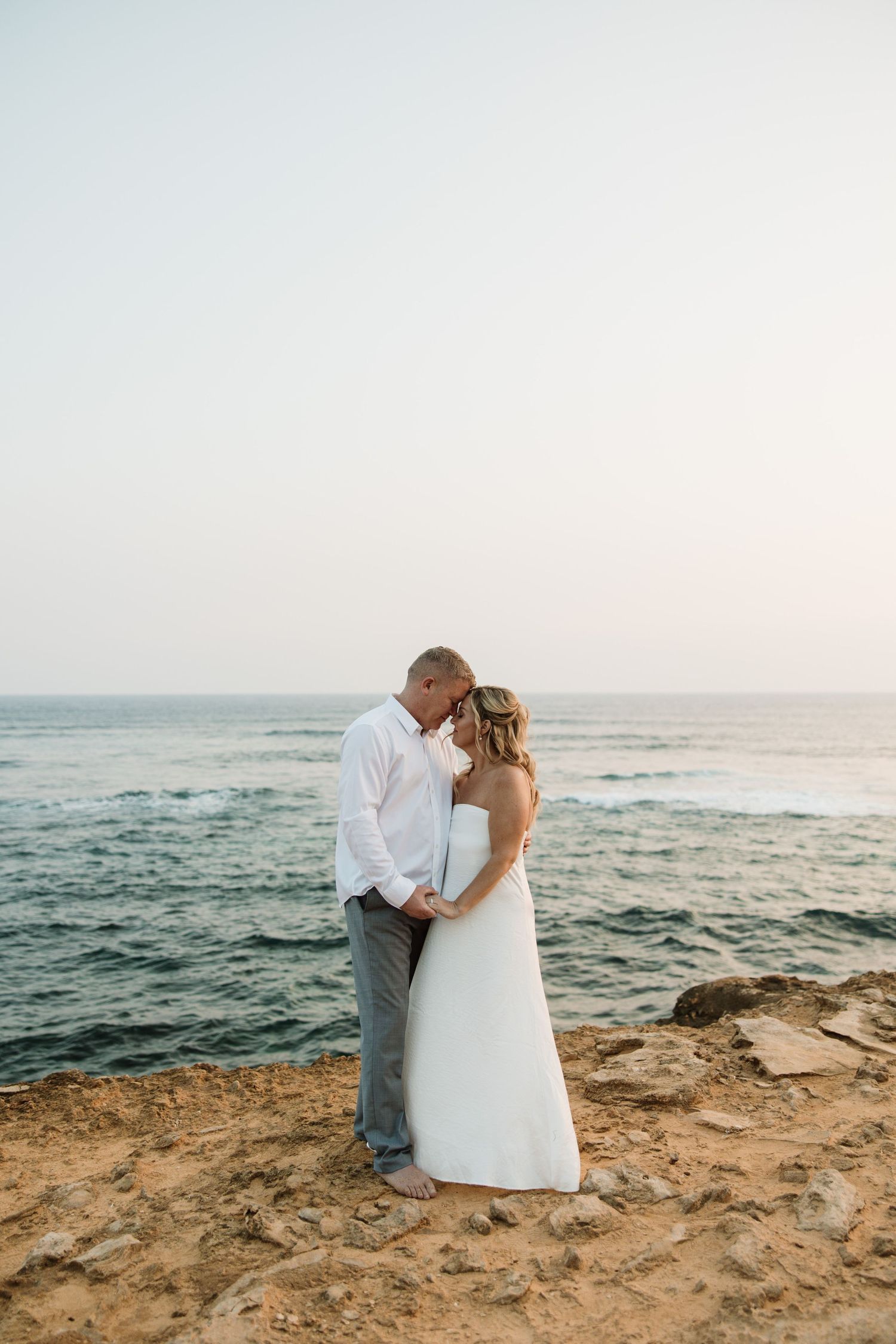 A romantic sunset moment on rocky ocean cliffs.