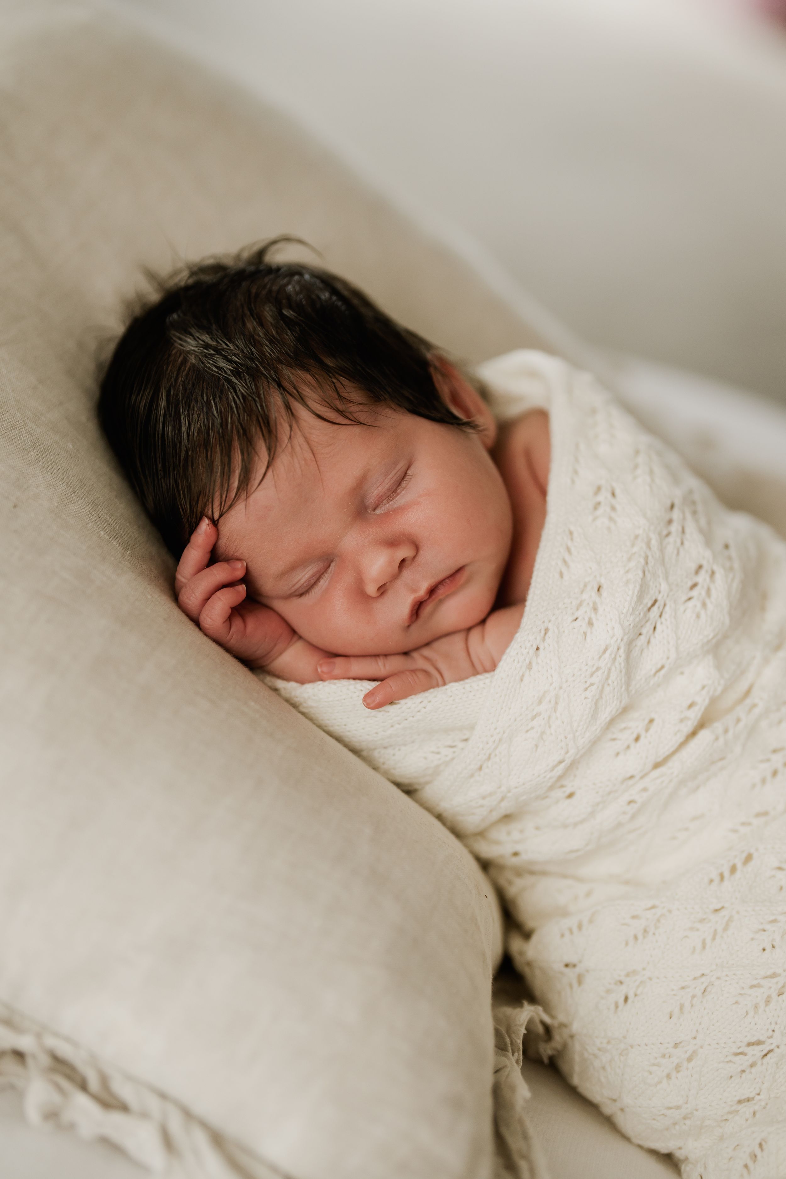 Sleeping newborn baby wrapped in a cream blanket during an in-home newborn photography session