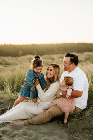 Relaxed lifestyle family photography in Christchurch – parents sitting on sand dunes with toddler and baby