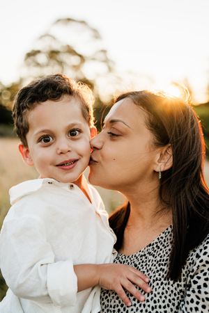 Candid family moment – mother kissing young boy at sunset during Christchurch photography session