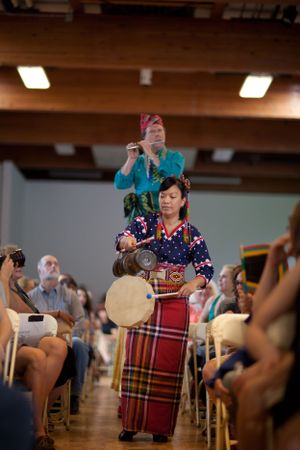 Performers in colorful traditional dress presenting during an indoor cultural show.