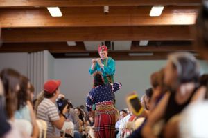 Performers in traditional costumes entertaining an indoor audience.