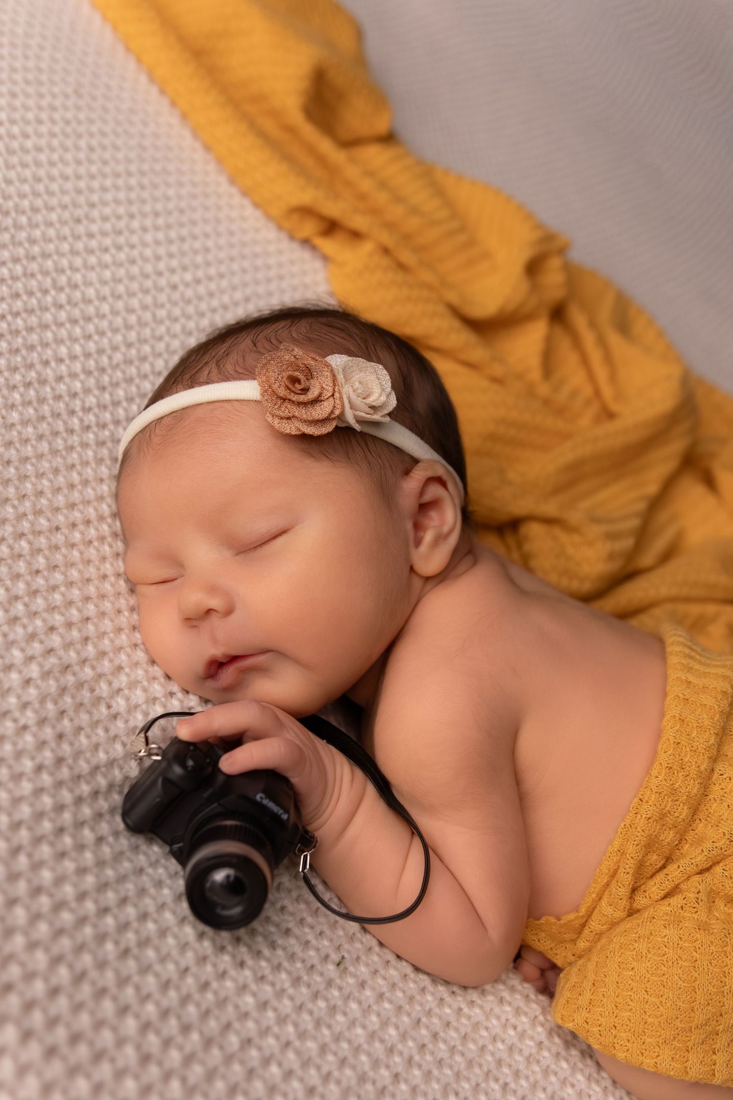 Artistic newborn photography sequence with vintage camera prop and yellow accessories.
