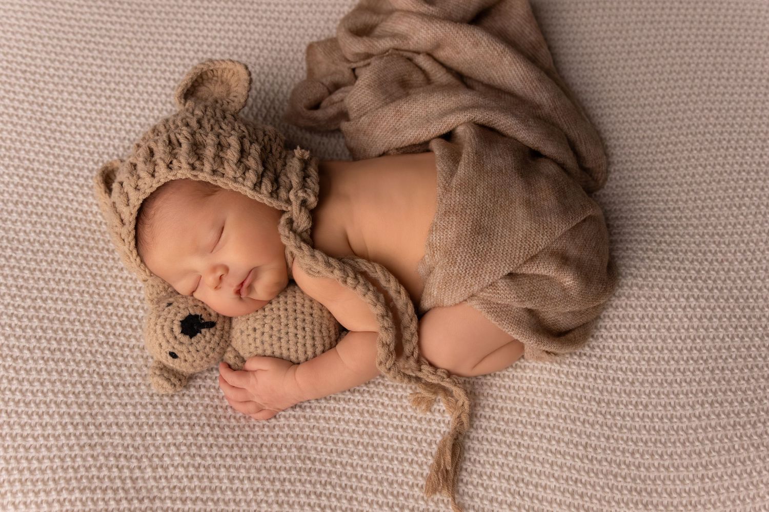 Professional newborn photo series with brown textured blanket and crown accessory.