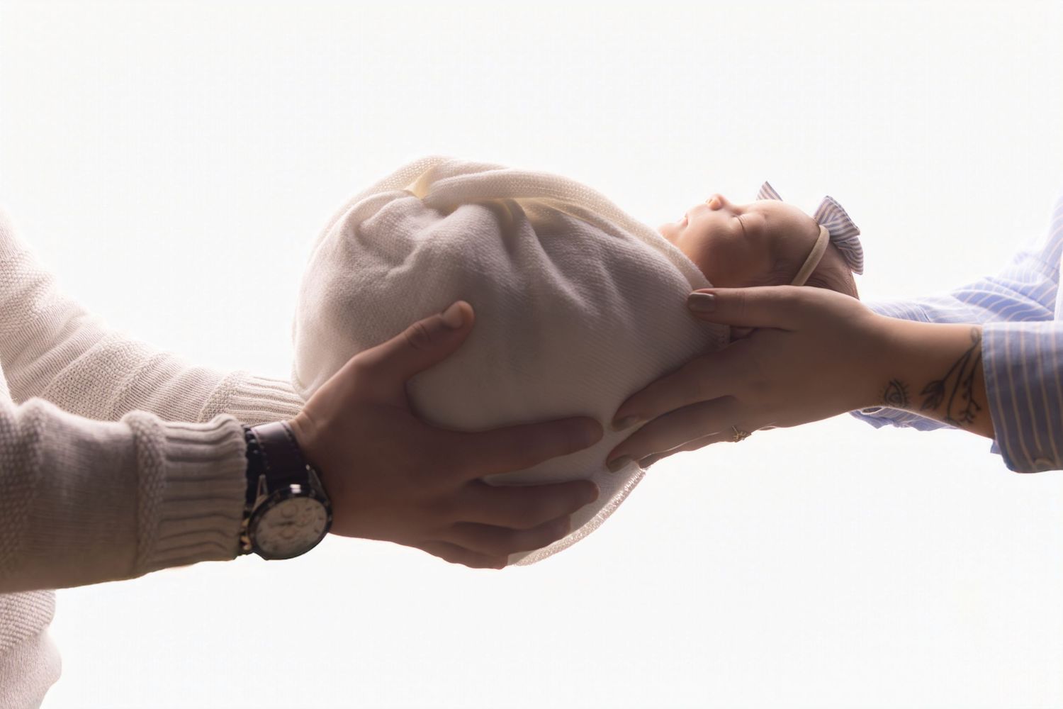Creative sequence of hands cradling and supporting a newborn against white background.