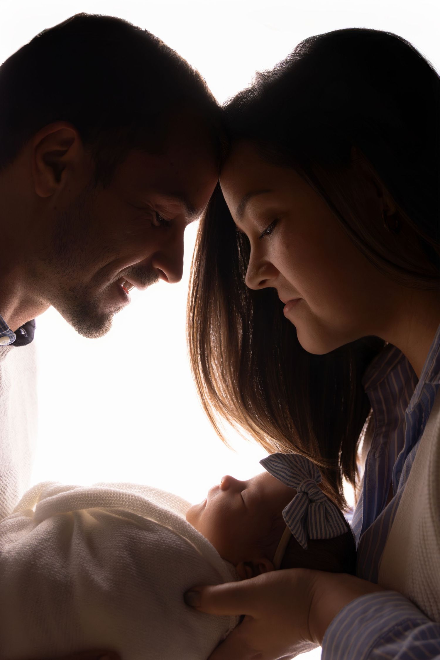 Silhouetted family portrait series with dramatic backlighting creating intimate moments.