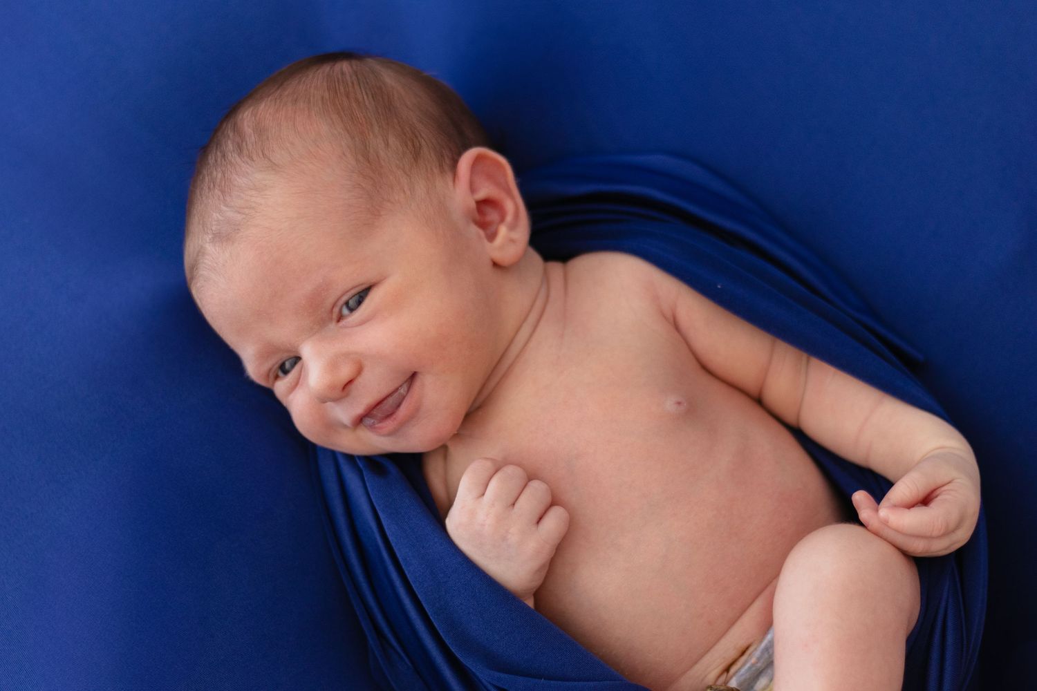 Professional newborn photography against deep blue background.