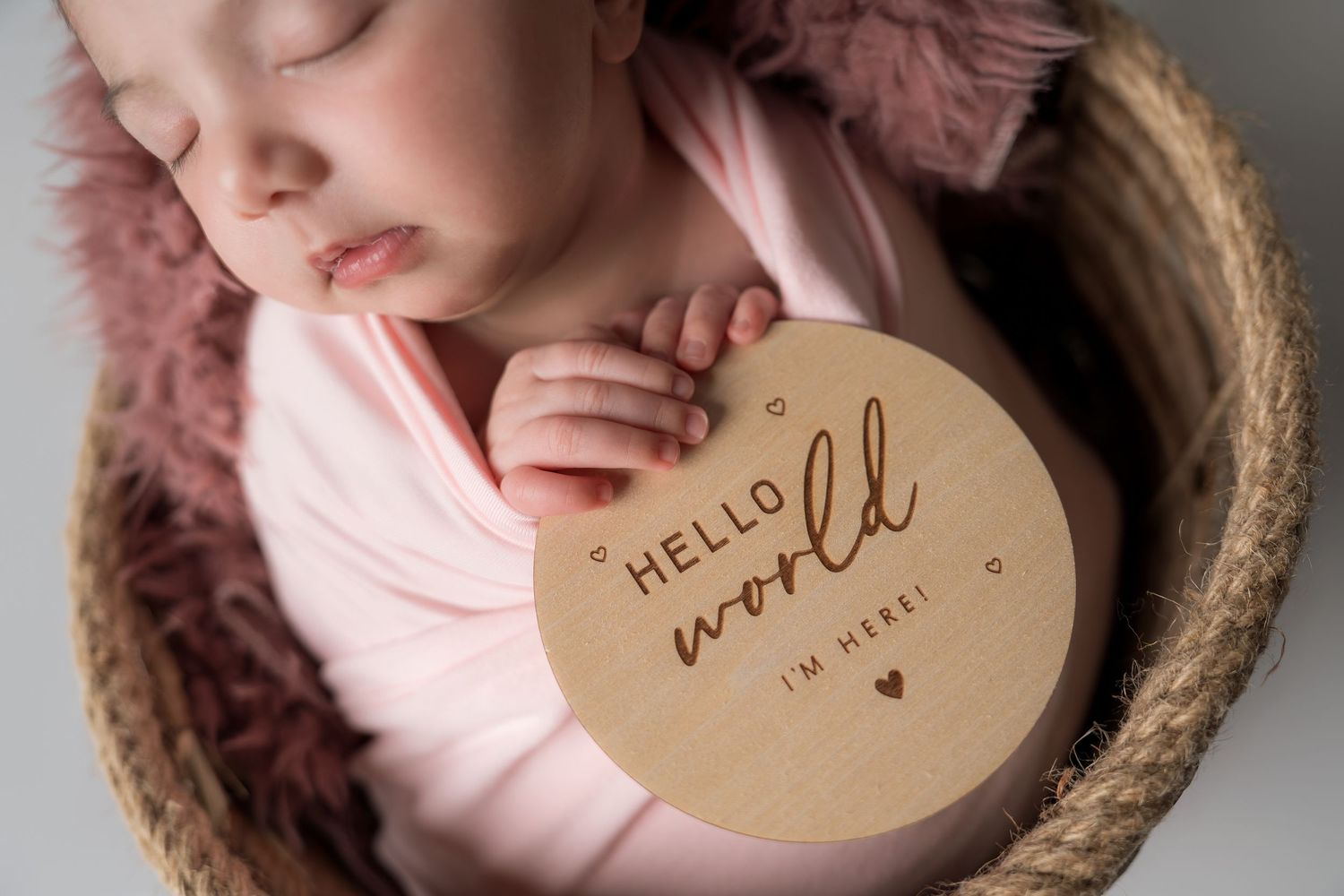 A kraft paper tag with gold lettering that reads 'hello' is nestled in soft pink fabric and natural twine.