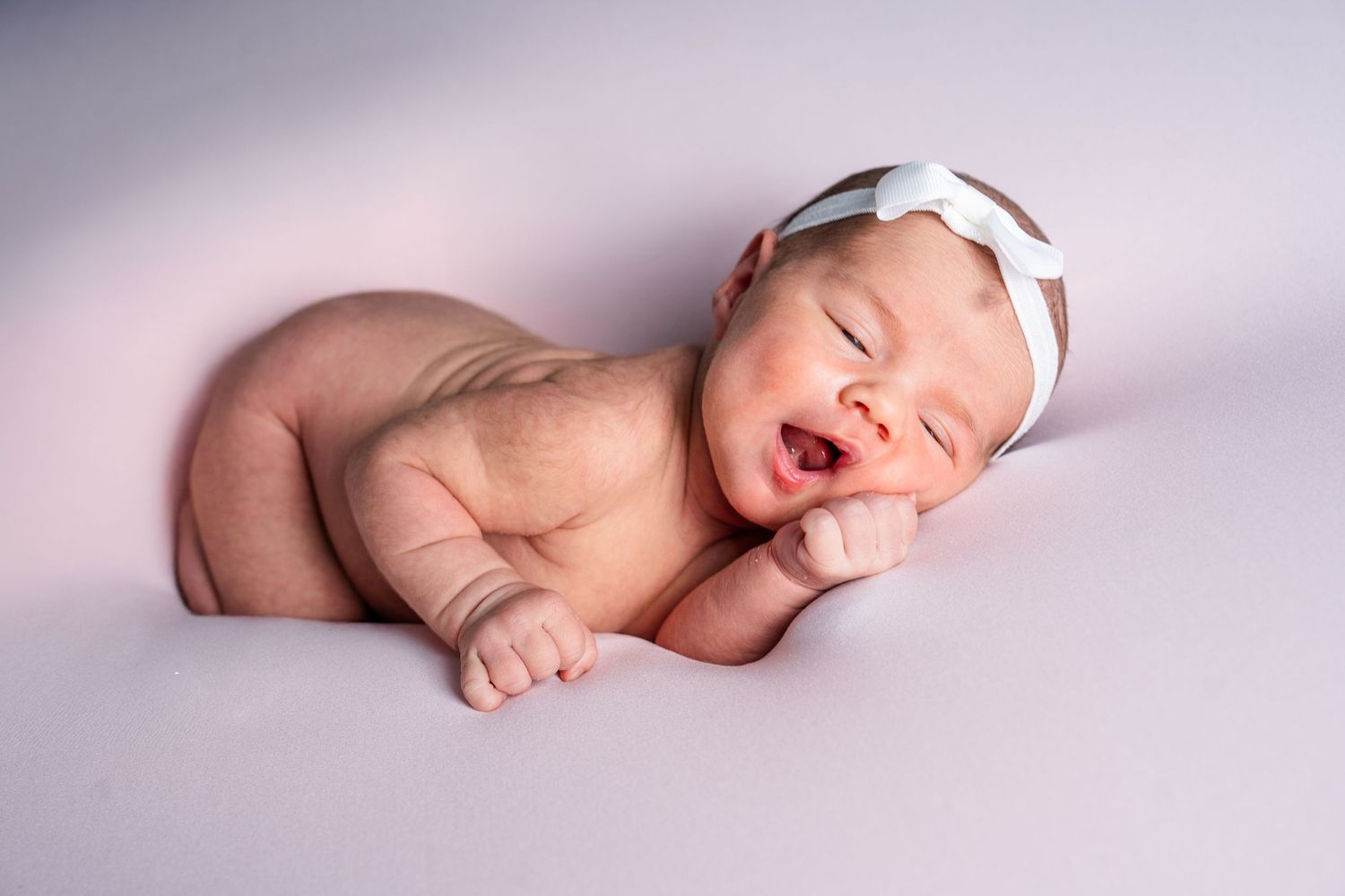 Sleeping newborn baby posed in various peaceful positions against soft purple background.