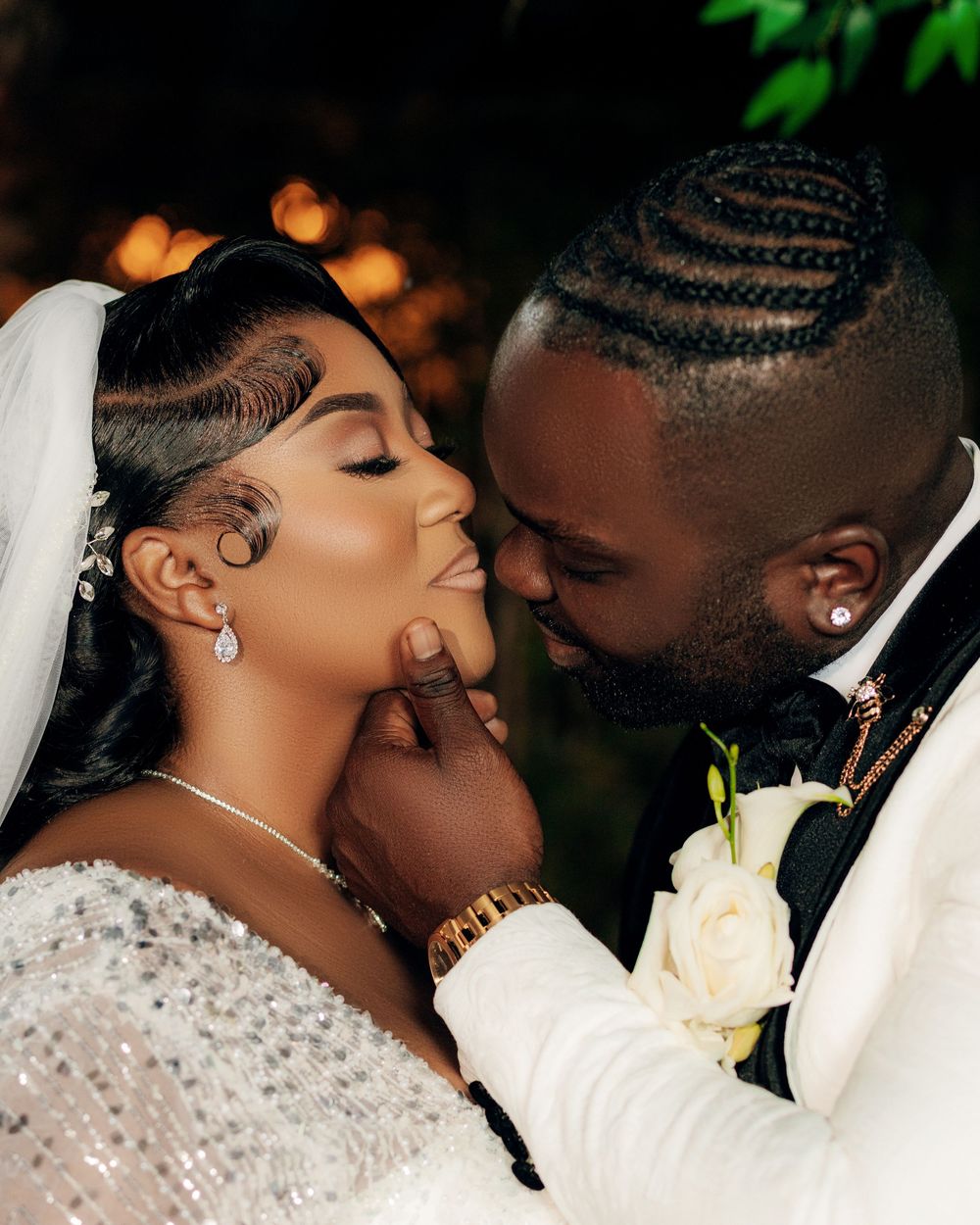 A romantic wedding couple share a tender moment amidst bokeh lights and elegant floral decor.