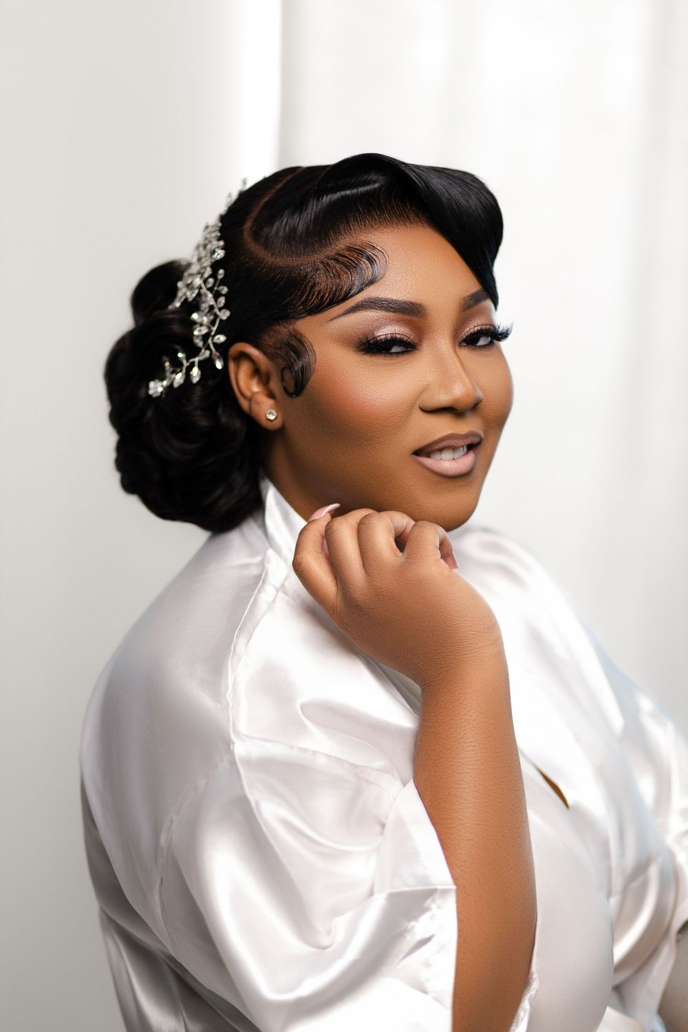 Elegant bridal portrait in white silk robe with vintage-inspired hairstyle adorned with pearl hair accessories.