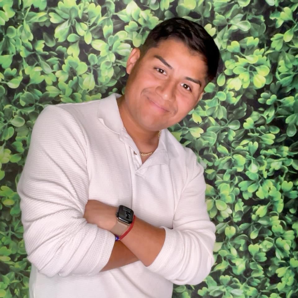 man posing in a white shirt, leaves in background