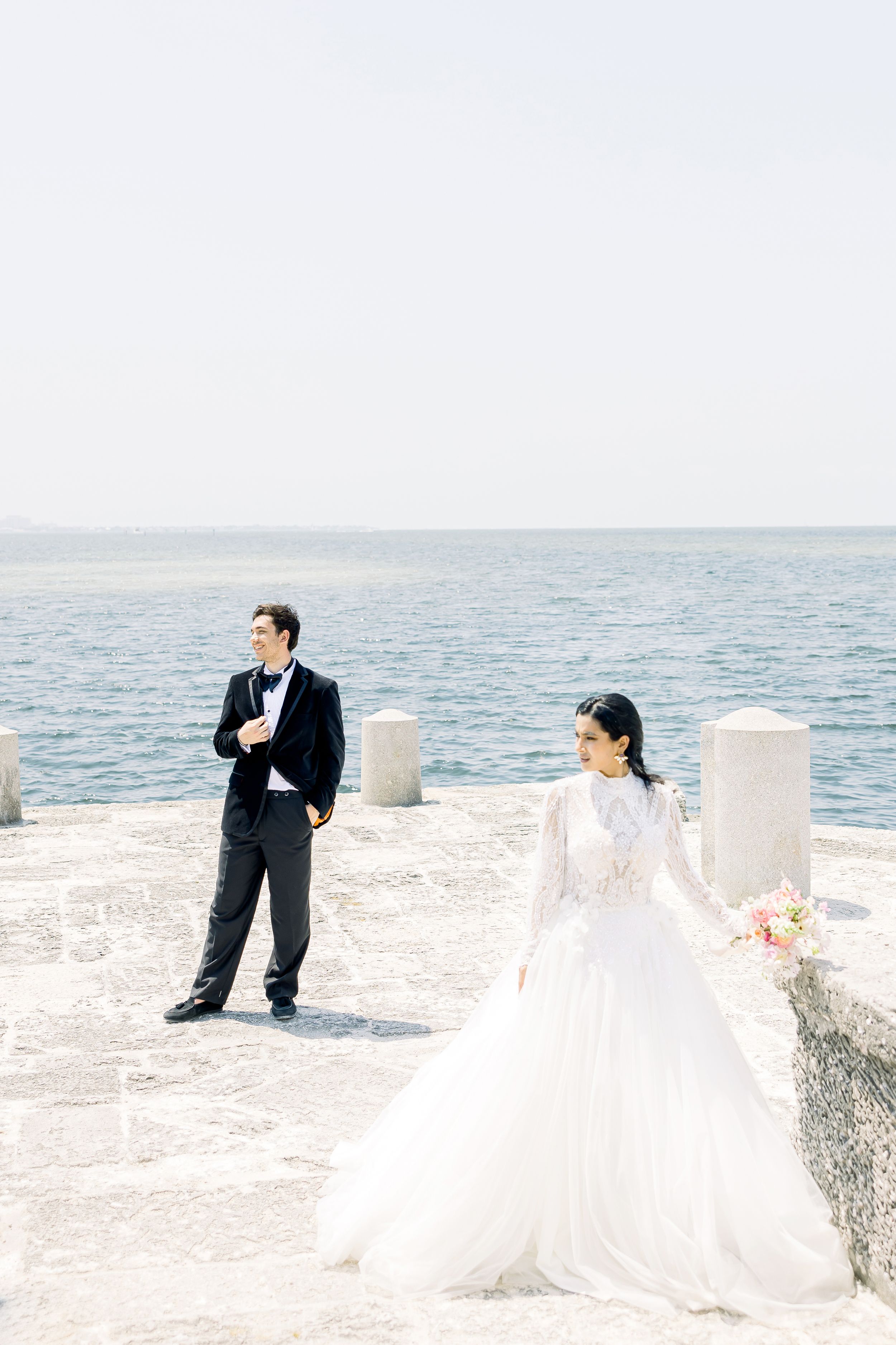 Seaside wedding portrait with couple on white stone terrace overlooking ocean.