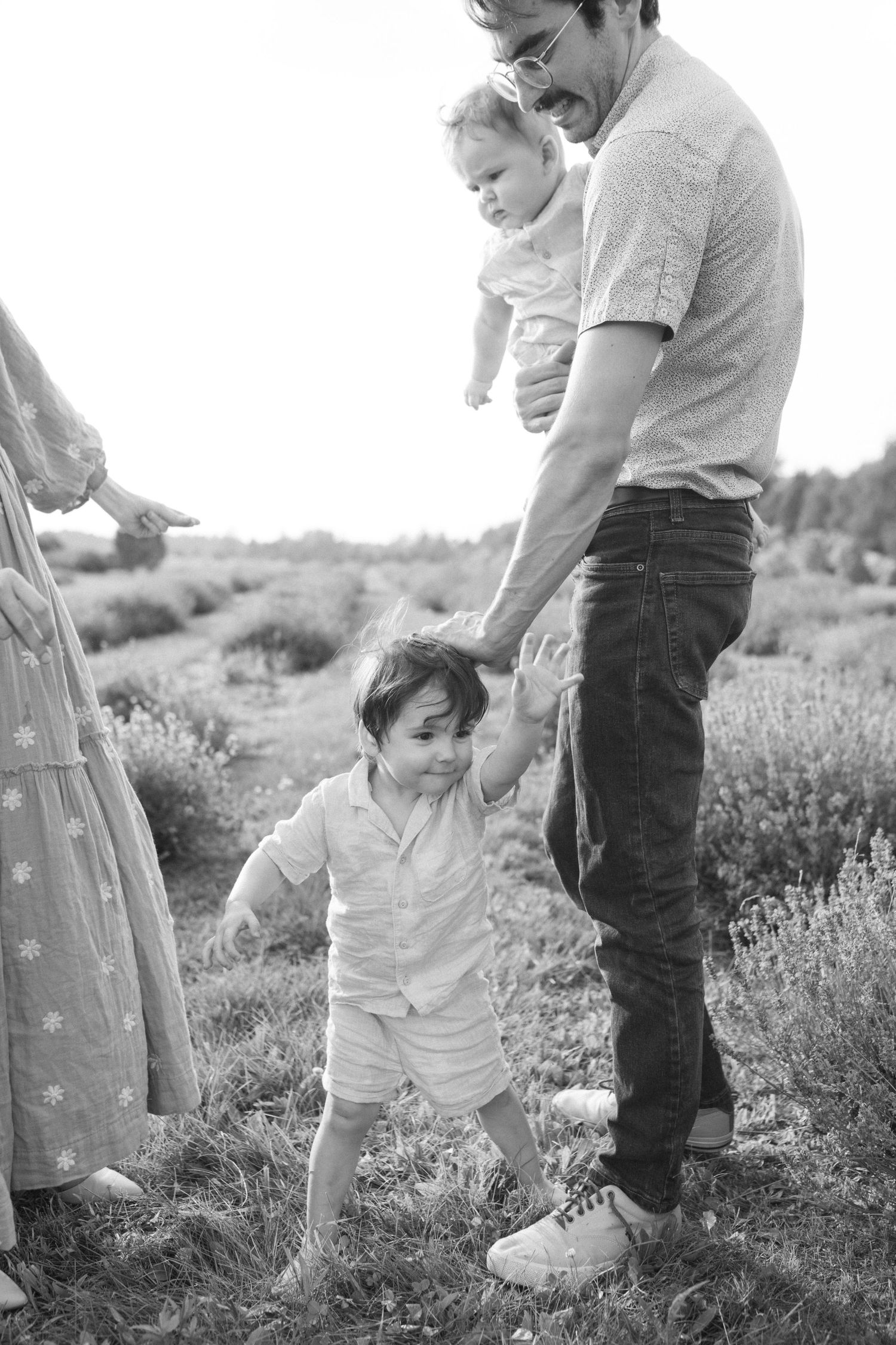 Family enjoying outdoor moment together in field of flowers.
