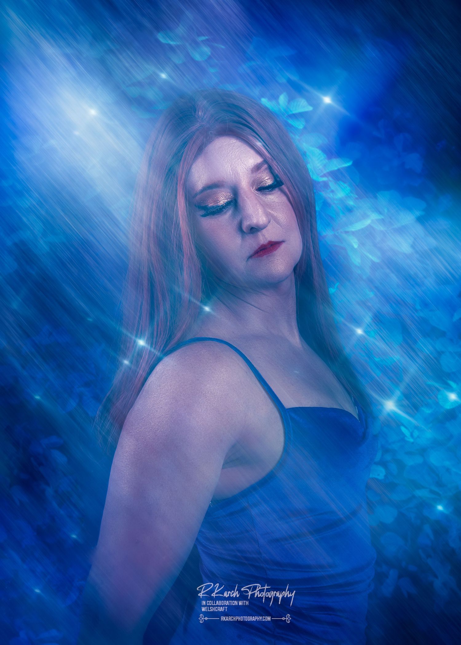 Ethereal artistic portrait against a glowing deep blue background with sparkles and mystical lighting effects.