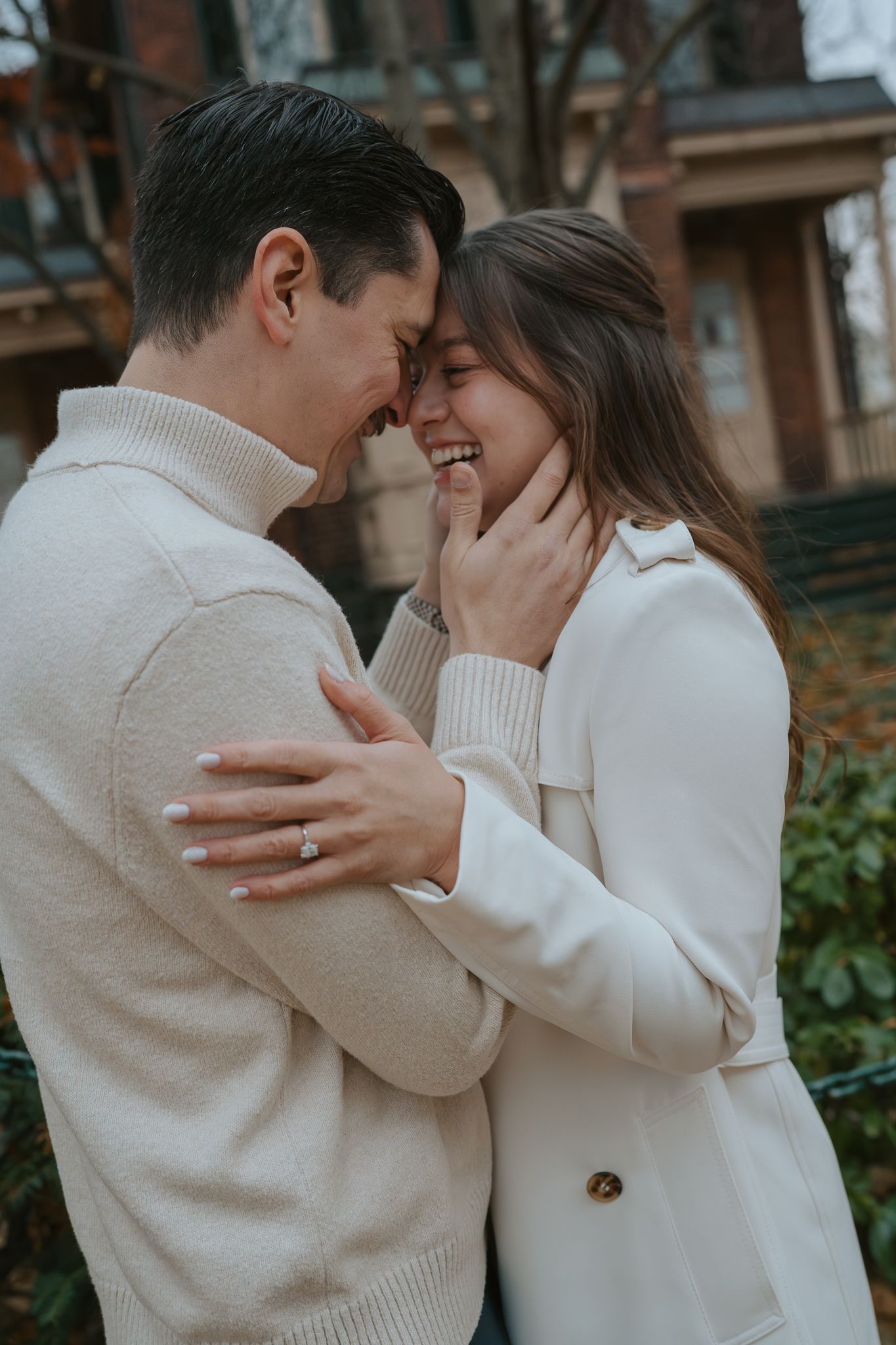Couple in cream colored winter outfits share playful moments in a downtown area