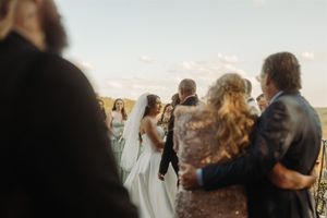 Wedding guests gather at sunset to watch a scenic outdoor ceremony.