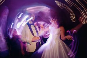 A couple dances under purple lights creating swirling light trails at their wedding reception.