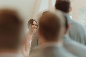 A soft focus wedding ceremony moment captured through silhouetted guests in the foreground.