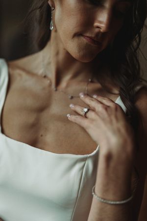 Close-up detail of an elegant white wedding dress and sparkling jewelry including bracelet and engagement ring.