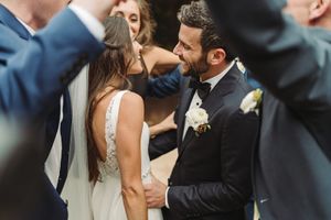 A couple shares an intimate moment at their wedding ceremony wearing formal attire with a white gown and black suit.